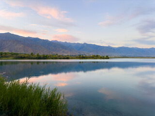 Quiet mountain lake, evening light on the water, Kyrgyzstan. Still water and mountain reflection in the lake