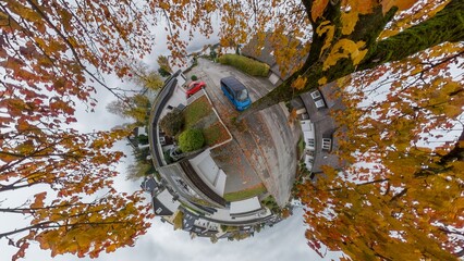 Camera looks down from a maple tree crown onto a housing estate in Germany from a bird's eye view....