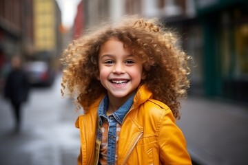 Portrait of a beautiful little girl with curly hair in the city