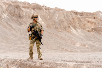 Military or soldier with gun stand in battlefield near the mountain and look to right side during...
