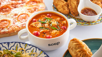 Asian tomato soup with potatoes and shrimps on the background of other Asian dishes