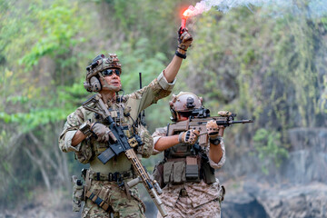 Close up two militaries or soldiers stay in battlefield near the river with one hold flare...