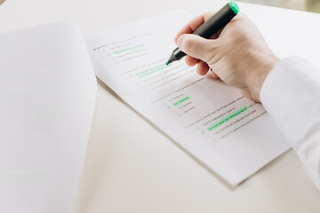 a man uses a marker to highlight important data in a document. indicates errors, editor.