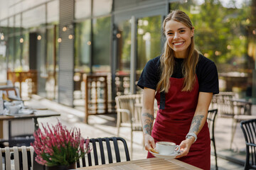 A cheerful barista presenting a cup of coffee in a stylish caf setting