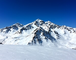 Obraz premium Breathtaking view of snow-covered mountains under a clear blue sky, perfect for winter sports and nature enthusiasts.