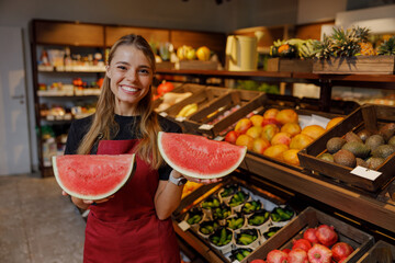 A cheerful woman happily showcases fresh, juicy watermelon slices in a vibrant grocery store setting full of life