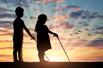 Silhouettes of two blind children, a boy and a girl, walking together at sunset.