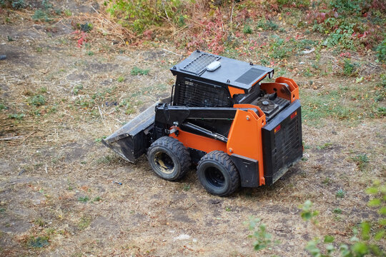 Mini-loader prepares the site for construction, loader at work cleaning the area, mini-loader operation, beginning of construction work