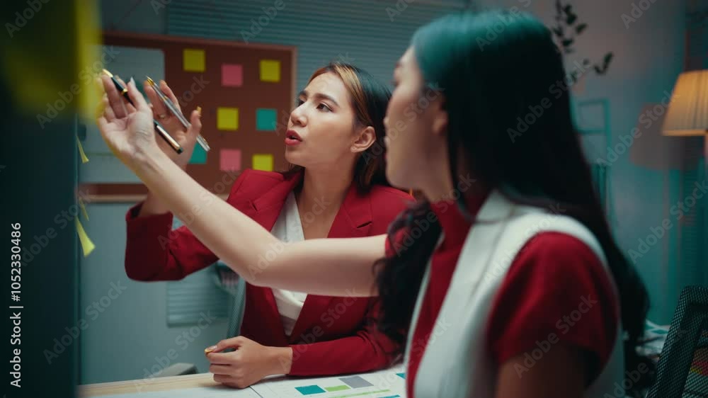 Poster two young businesswomen engage in a lively discussion while utilizing colorful sticky notes on a gla