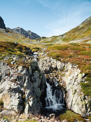 Mountain stream in alpine valley. Waterfall near Flüela mountain Pass road between Silvretta and Albula mountain ranges.