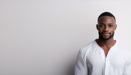 Obraz premium A young black man wearing white clothes in front of white wall