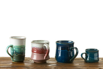 Group of variety ceramic cups on a wooden table. White background.