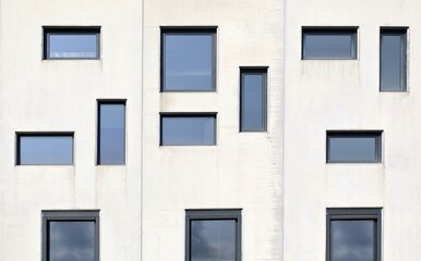 Fototapeta premium Pvc windows with different shapes and size on a precast concrete facade. Background and texture.