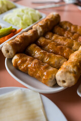 Vietnamese Grilled Pork Sausage eating with herbs, chili, garlic, raw banana, raw mango, Chinese noodle with sweet-spicy sauce, sprinkled with peanuts and a variety of fresh vegetables