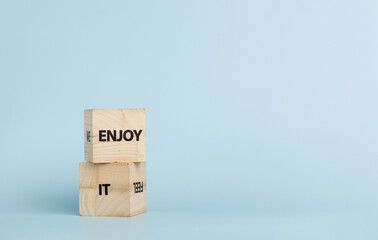 Wooden cubes with inscriptions Enjoy It on a blue background