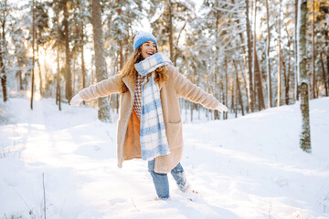 Happy woman laughing and enjoying a snowy winter day in the forest. Fashion style. Winter holidays.