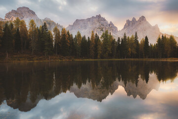 Mountain reflection on Lake Antorno mirrors of autumn colours of the surrounding forest and Cadini di Misurina peaks, creating a serene and tranquil scene in the Italian Dolomites.