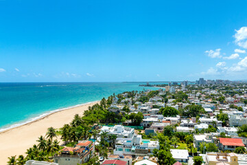 Aerial view of the residential community of Ocean Park in San Juan, Puerto Rico. Showcasing the wide sandy beaches, turquoise ocean, and filled with a tropical city skyline in the background.