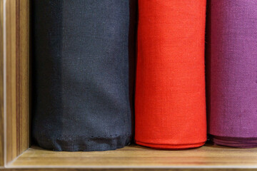 A fabric store. There are rolls of fabrics in different colors on the shelves. The yarn business. Tailoring of clothes and bed linen made of natural linen or cotton.