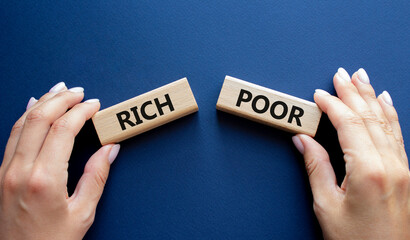 Rich vs Poor symbol. Concept word Rich vs Poor on wooden blocks. Businessman hand. Beautiful deep blue background. Business and Rich vs Poor concept. Copy space