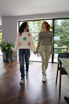 Women holding hands at home