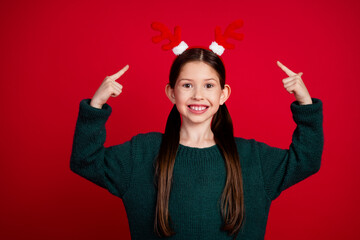 Photo portrait of pretty small girl point up show deer headband wear green christmas outfit theme...