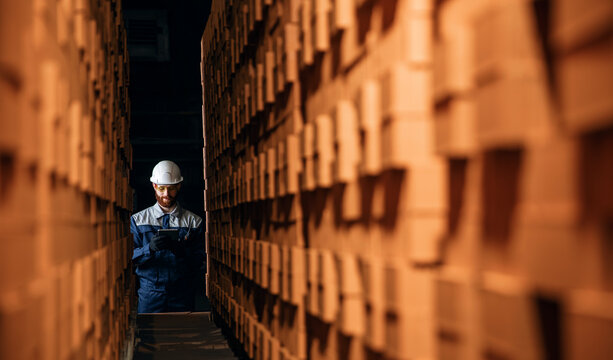 Portrait man worker holding clipboard for control quality of bricks. Production line of ceramics factory