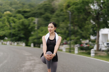 Runner's Rest: A serene portrait of a young woman runner taking a break, stretching her leg on a...