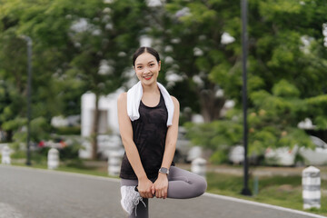 Post-Workout Serenity: A young woman runner stretches in a park, towel around her neck, smiling serenely after a refreshing run.  A feeling of accomplishment and well-being. 