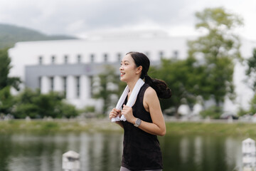 Runner's High: A young woman radiates joy as she runs along a scenic path, her towel draped around...