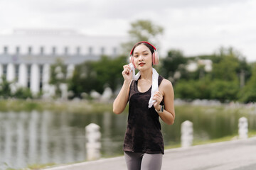 Fitness Journey:  A determined woman in sportswear walks confidently, headphones on, after a workout in a tranquil park setting, her energy and focus palpable.  