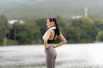 Active Woman by the Lake: A fit young woman takes a break after a workout, enjoying the serene view...