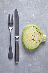 Obraz premium cabbage cut across and cutlery fork and knife on grey concrete table