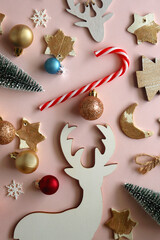 Various cute Christmas ornaments on pale pink background. Flat lay.