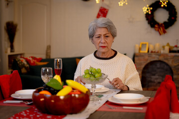 An elderly woman is lonely and sad celebrating Christmas at home.