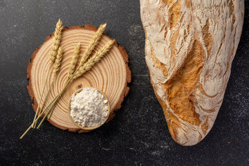 A rustic loaf of bread with unique textures sits alongside wheat stalks, placed creatively on a...