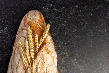 A rustic loaf of bread with unique textures sits alongside wheat stalks, placed creatively on a...