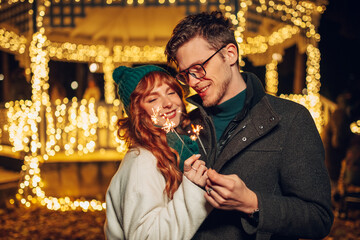 Obraz premium A festive young couple is celebrating christmas eve on a street.