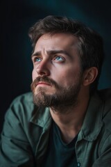 Obraz premium A bearded man with blue eyes looks upwards thoughtfully, exuding a sense of introspection and contemplation.