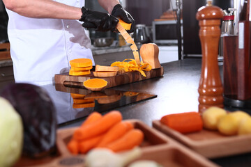 Fototapeta premium The cook is peeling a pumpkin. Cooking pumpkin soup. A pumpkin in his hands. The chef prepares a dish of vegetables.
