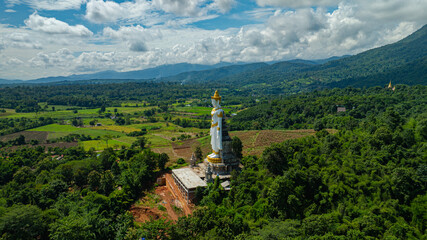 Fototapeta premium Big Buddha Brahma Panyo standing tall in front of Doi Luang mountain, Chiang Mai symbolizing peace and spirituality in a natural setting.Captured in an elevated rural area. High mountain background