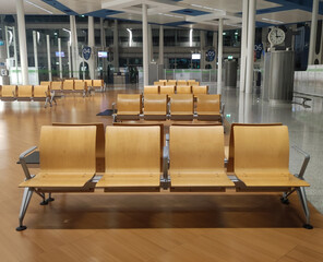 Airport waiting area with organized wooden benches and digital displays at night
