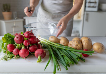 Woman in the kitchen with fresh ingredients for making a healthy potato salad