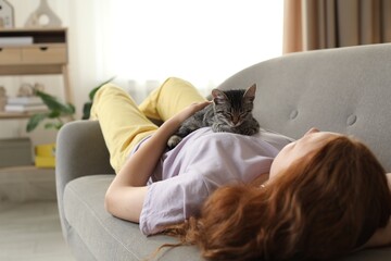 Teenage girl with cute cat on sofa at home © New Africa