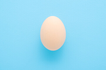 Brown egg on light blue table background. Pastel color. Closeup. Top down view.