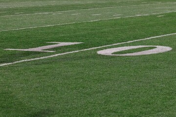Obraz premium Close-up of a football field's 10-yard line with vibrant green grass and white markings
