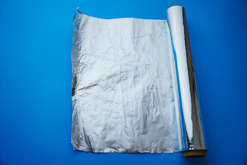 A roll of baking foil on a blue background. devices for delicious dishes in the kitchen.