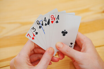 without a face. Hands of a man in a white t-shirt with cards during the game. gambling. A board game for spending leisure time with friends and family.