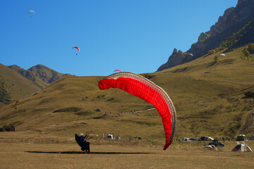 A landed pilot operates the opened dome on the ground against the backdrop of a high-altitude aero...