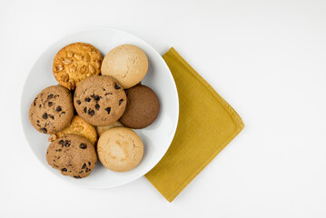 Different round cookies in white plate isolated on white background with copy space, top view.